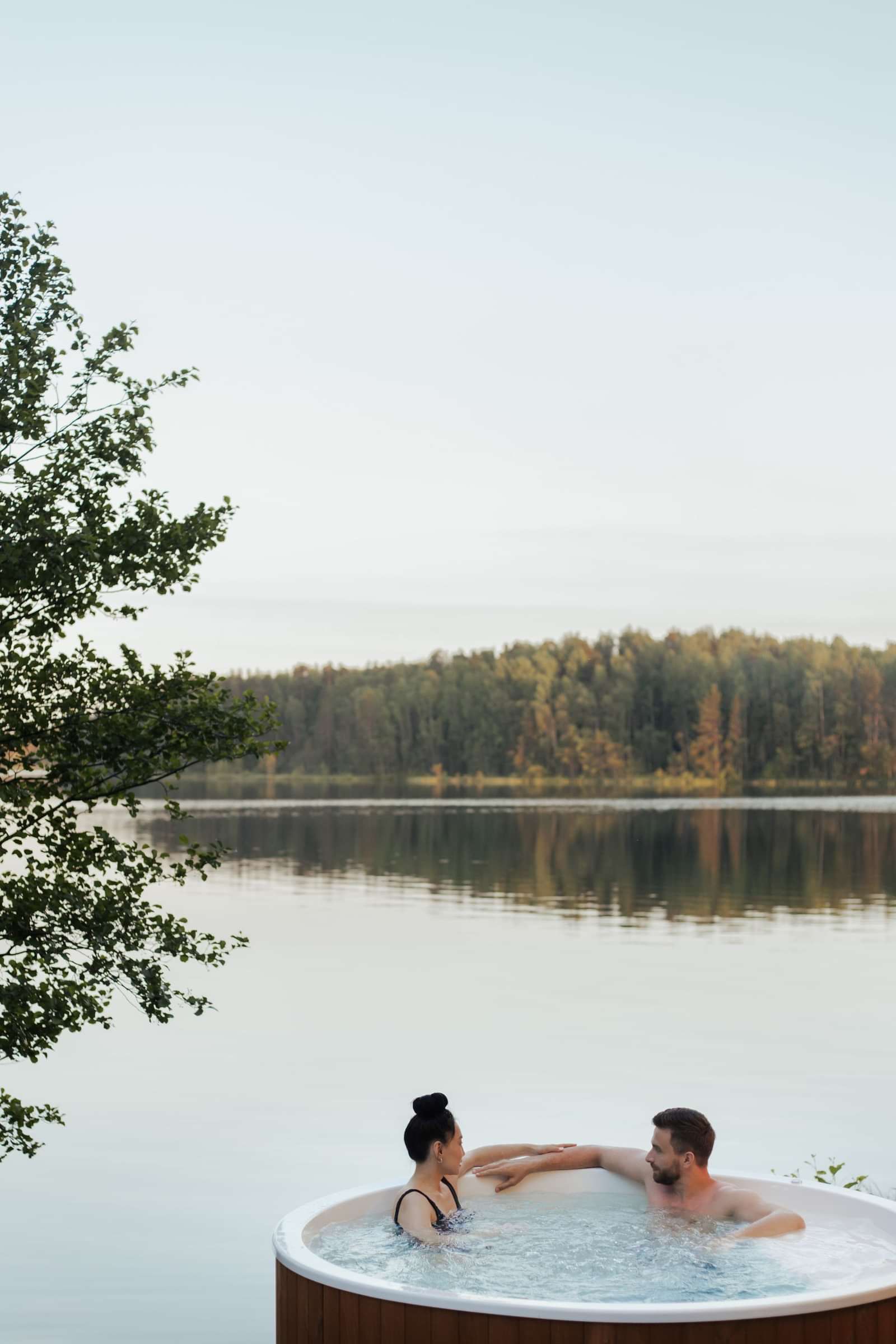 A couple relaxing in a hot tub by a lake